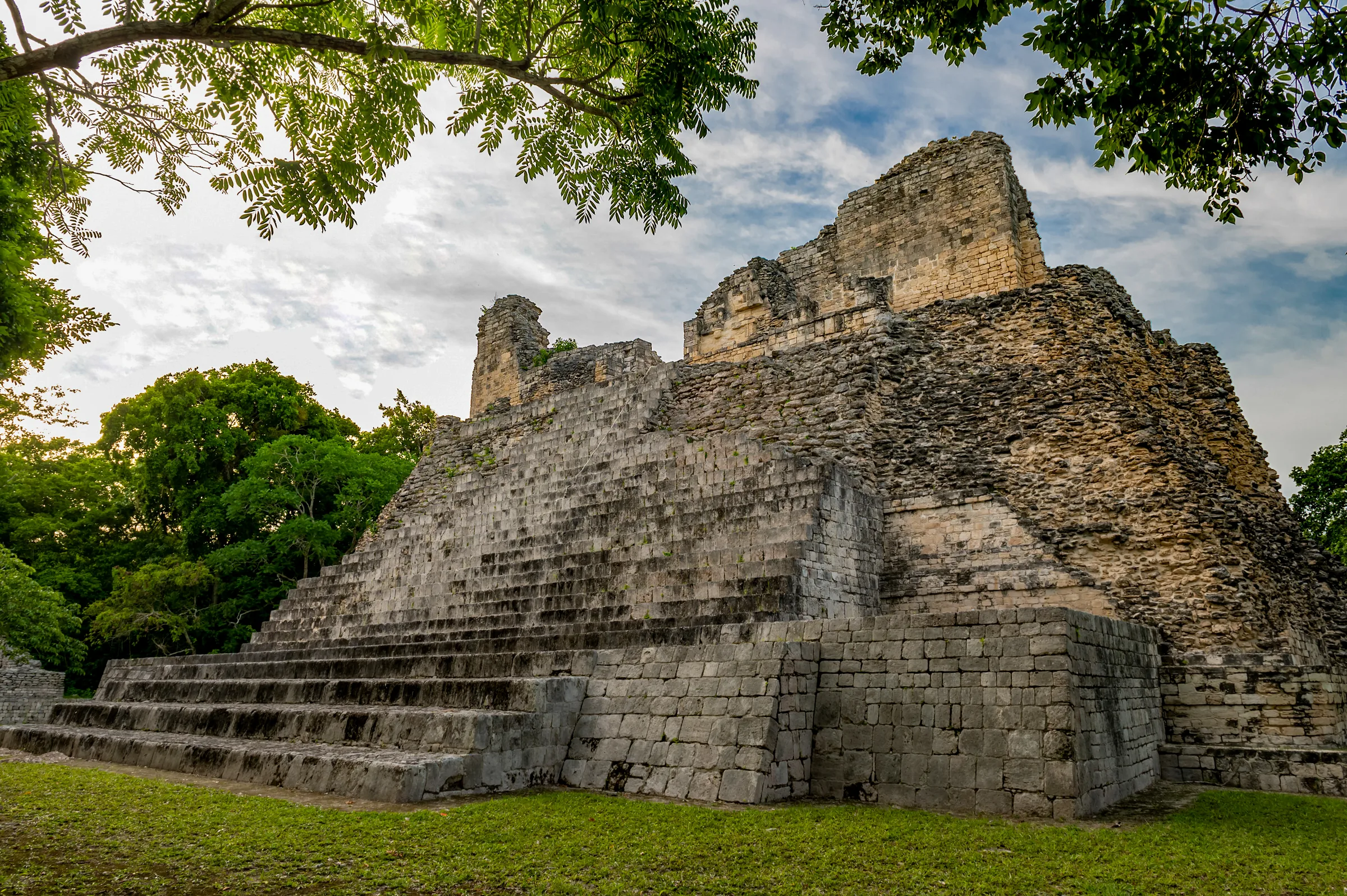 Main structure at Becán among trees, with lawn in the foreground