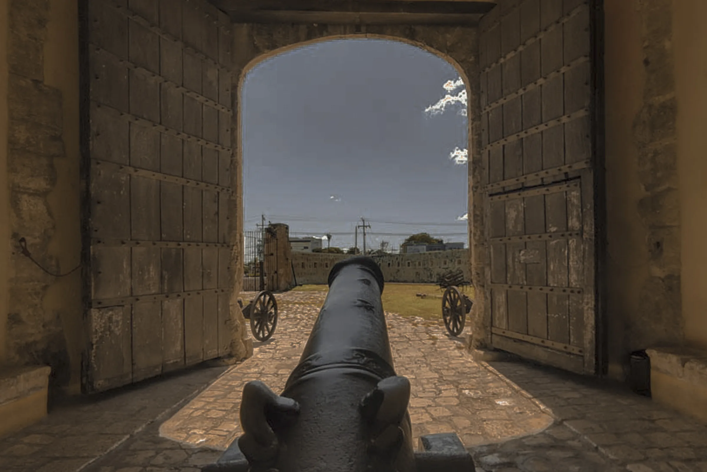 Cannon facing the open arch of the Puerta de Tierra in Campeche’s city walls, with its wooden doors