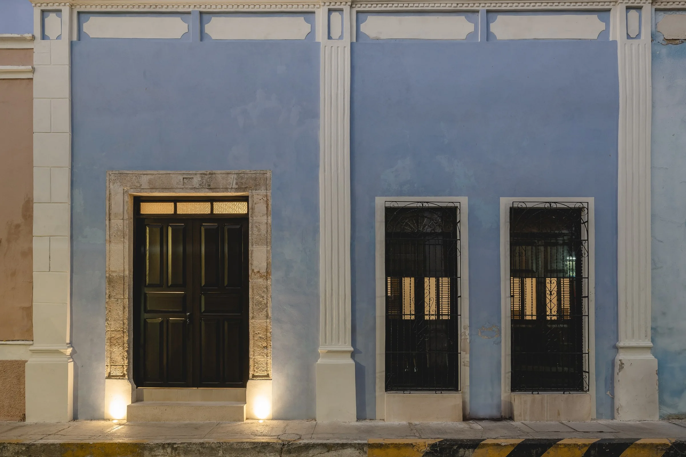Blue facade with white pilasters of Casa Estrada at dusk, in Campeche's walled city