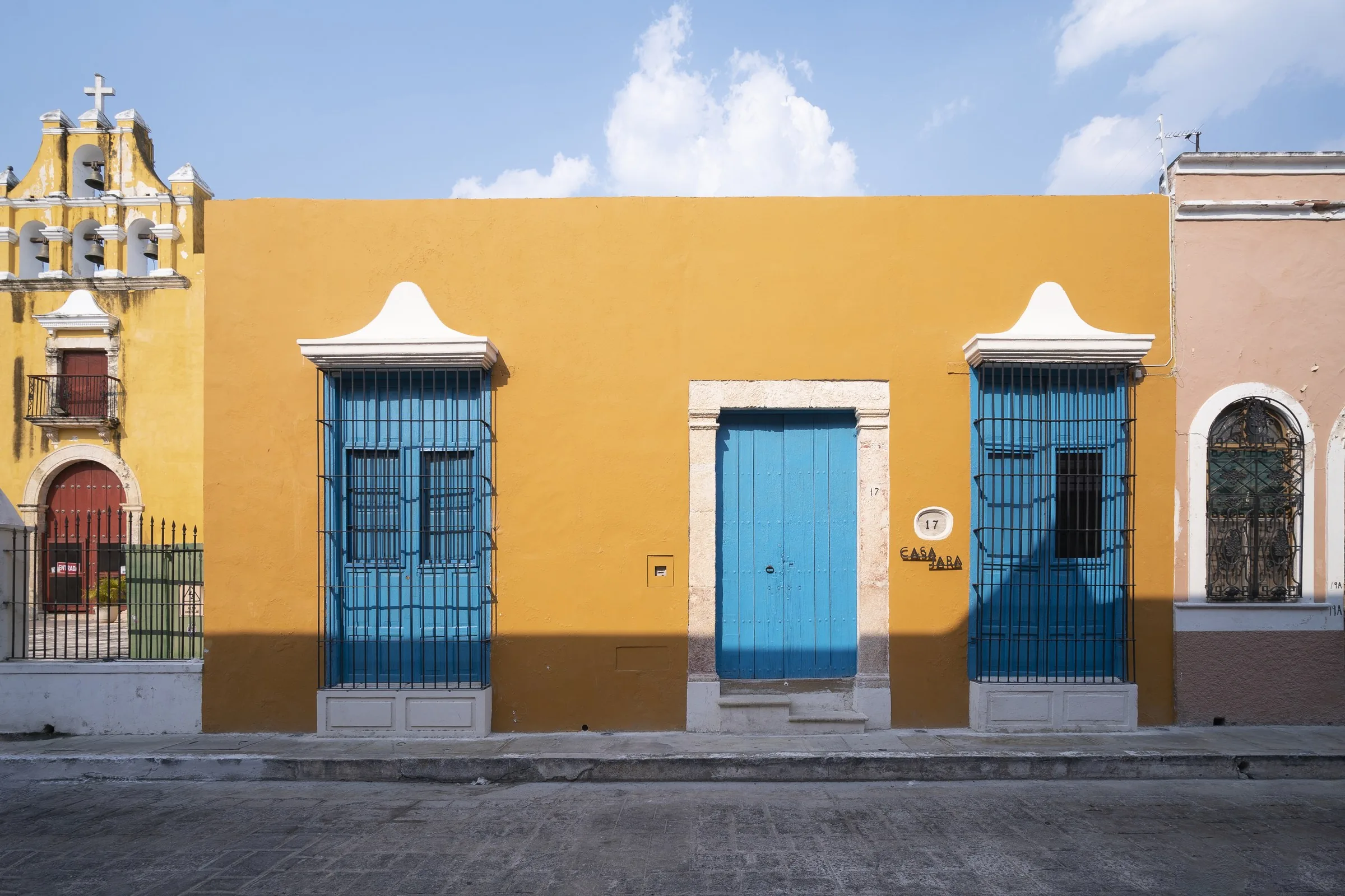Yellow facade of Casa Japa with blue door and windows on Calle 55, Campeche