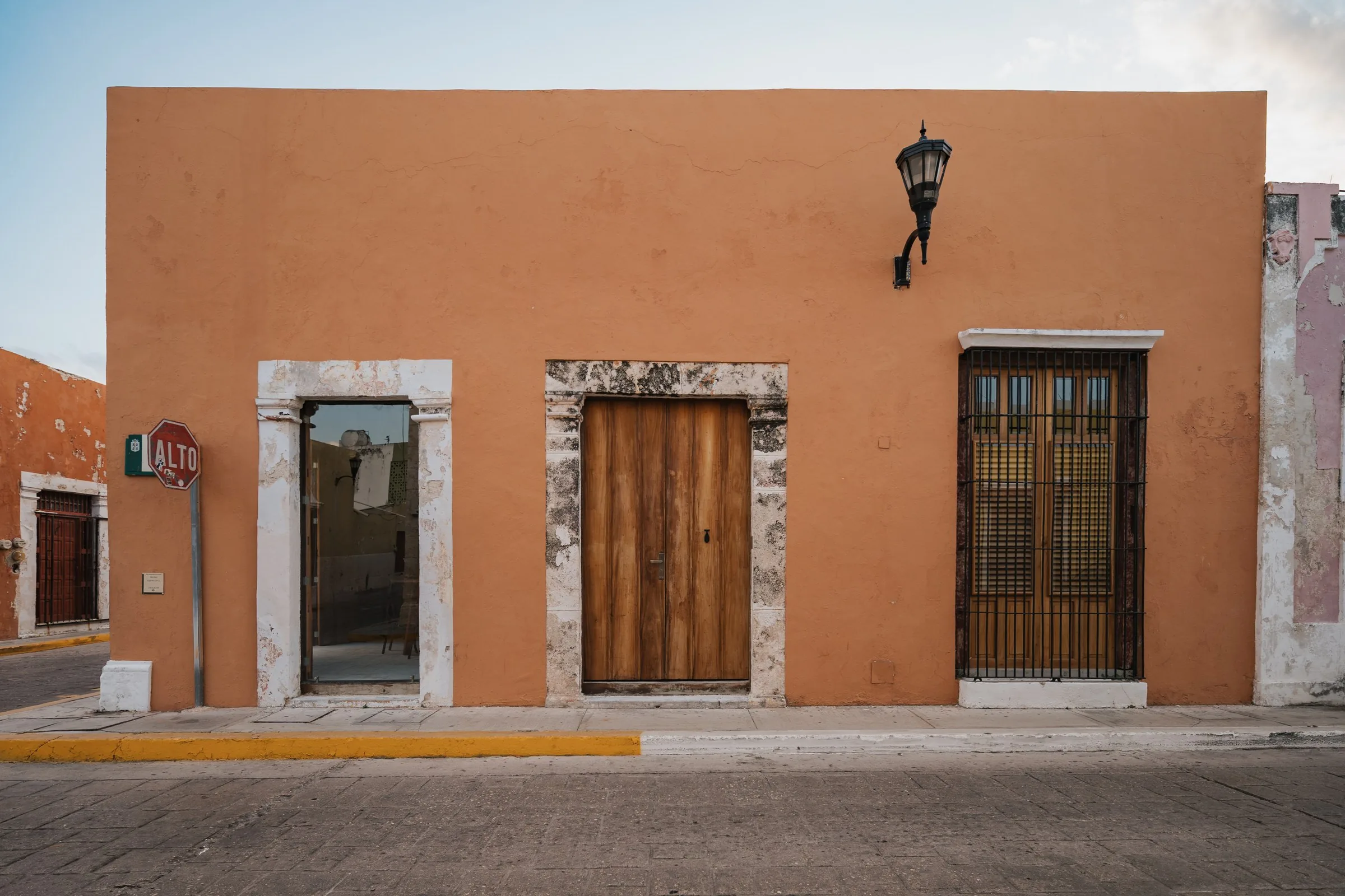 Terracotta facade of Casa Zotz with wooden doors and a lantern, in Campeche's walled city