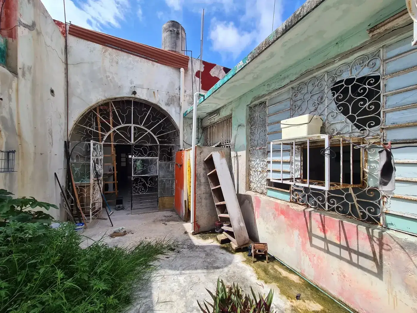 Arco y herrería de Casa Ex Templo antes de la restauración, entre vegetación y añadidos