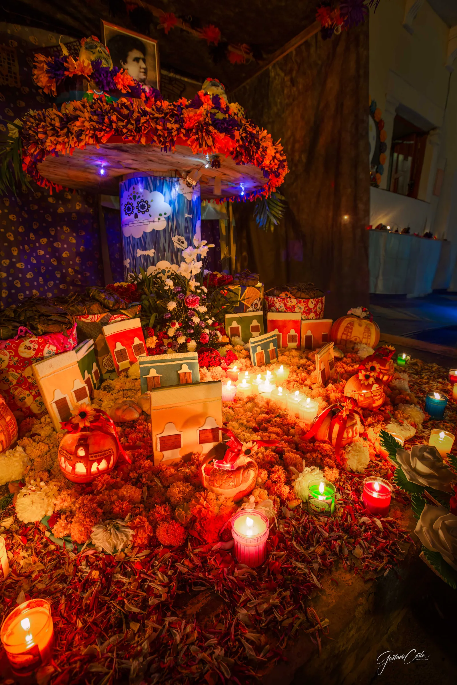 Hanal Pixán altar with small colorful houses, lit candles and marigolds