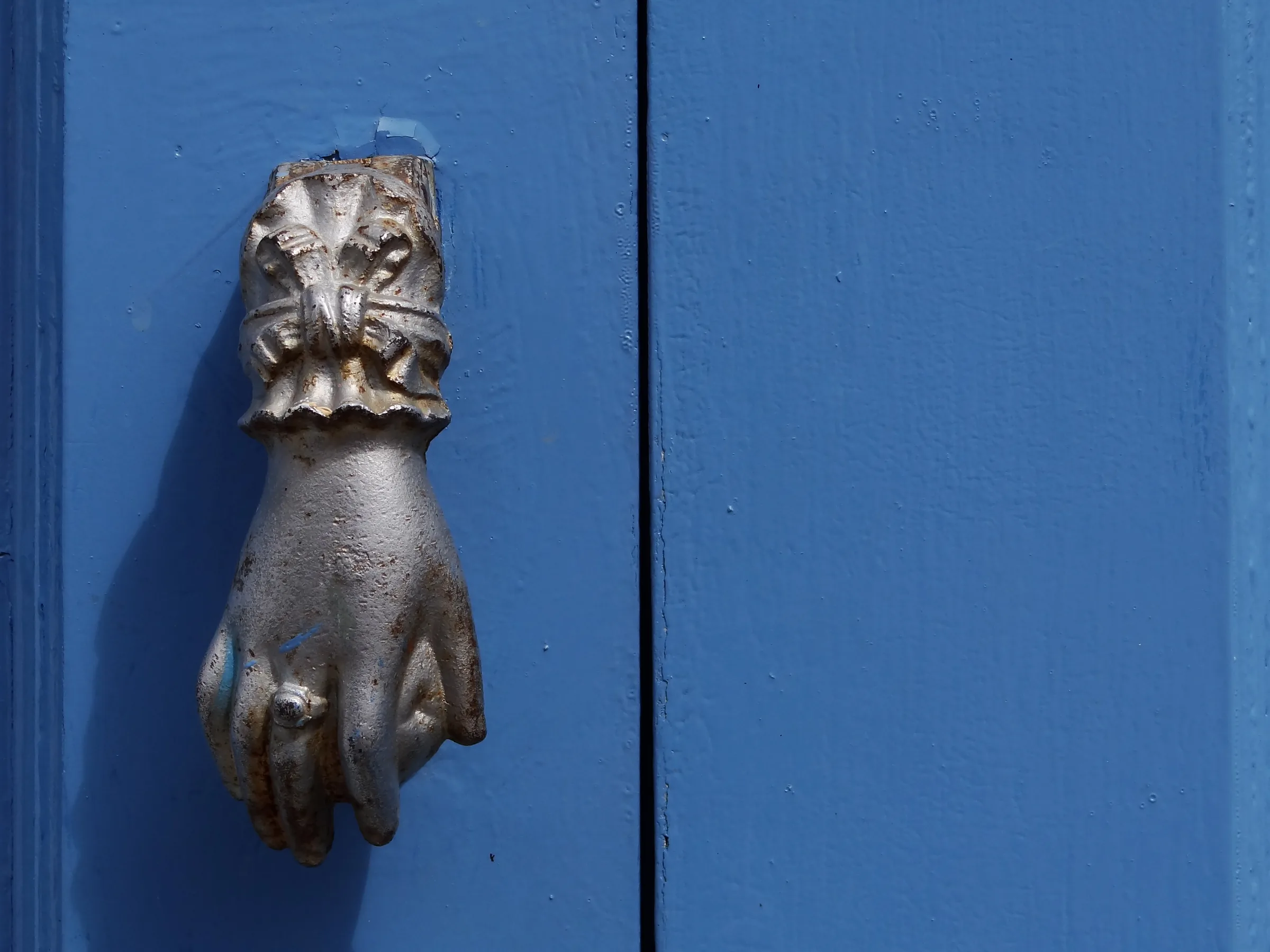 Hand-shaped iron door knocker on a blue-painted wooden door in Campeche's historic center