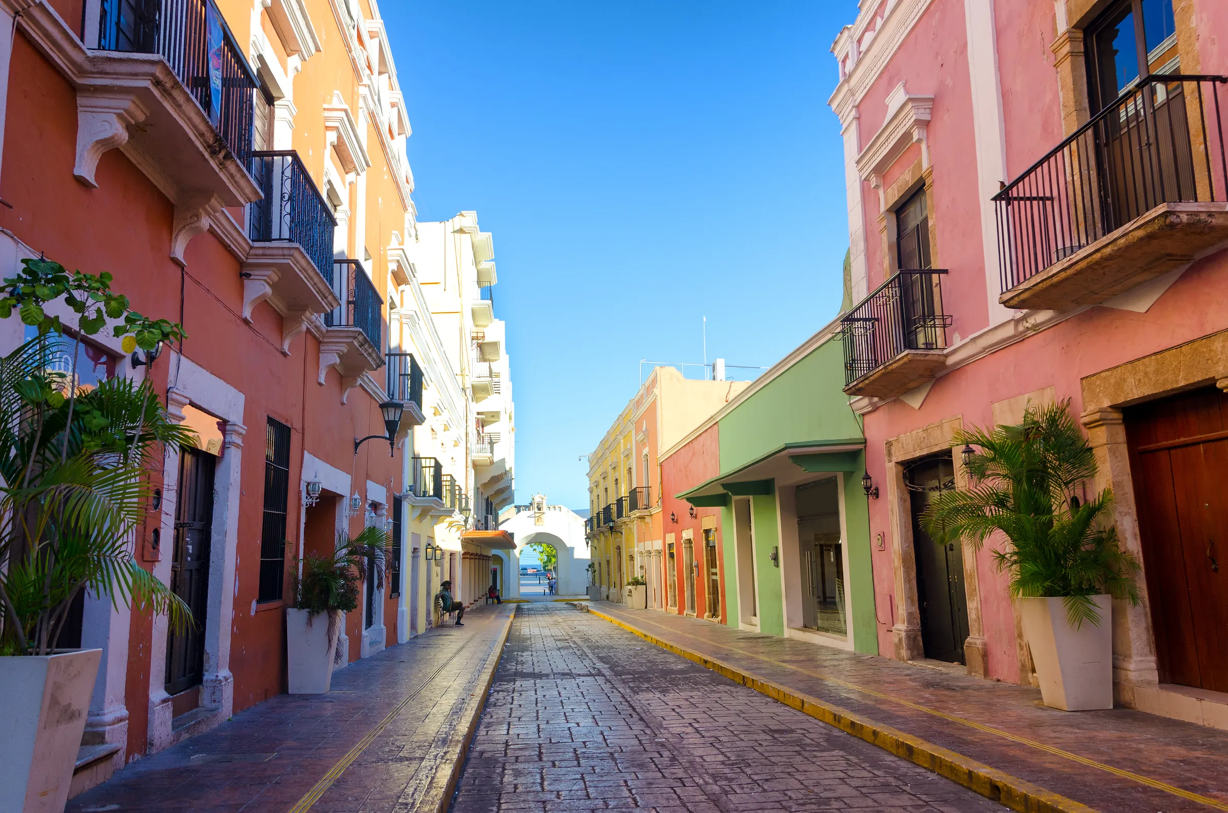 Calle 59 du centre historique de Campeche, avec des façades orange, jaune, verte et rose et la Puerta de Mar au fond