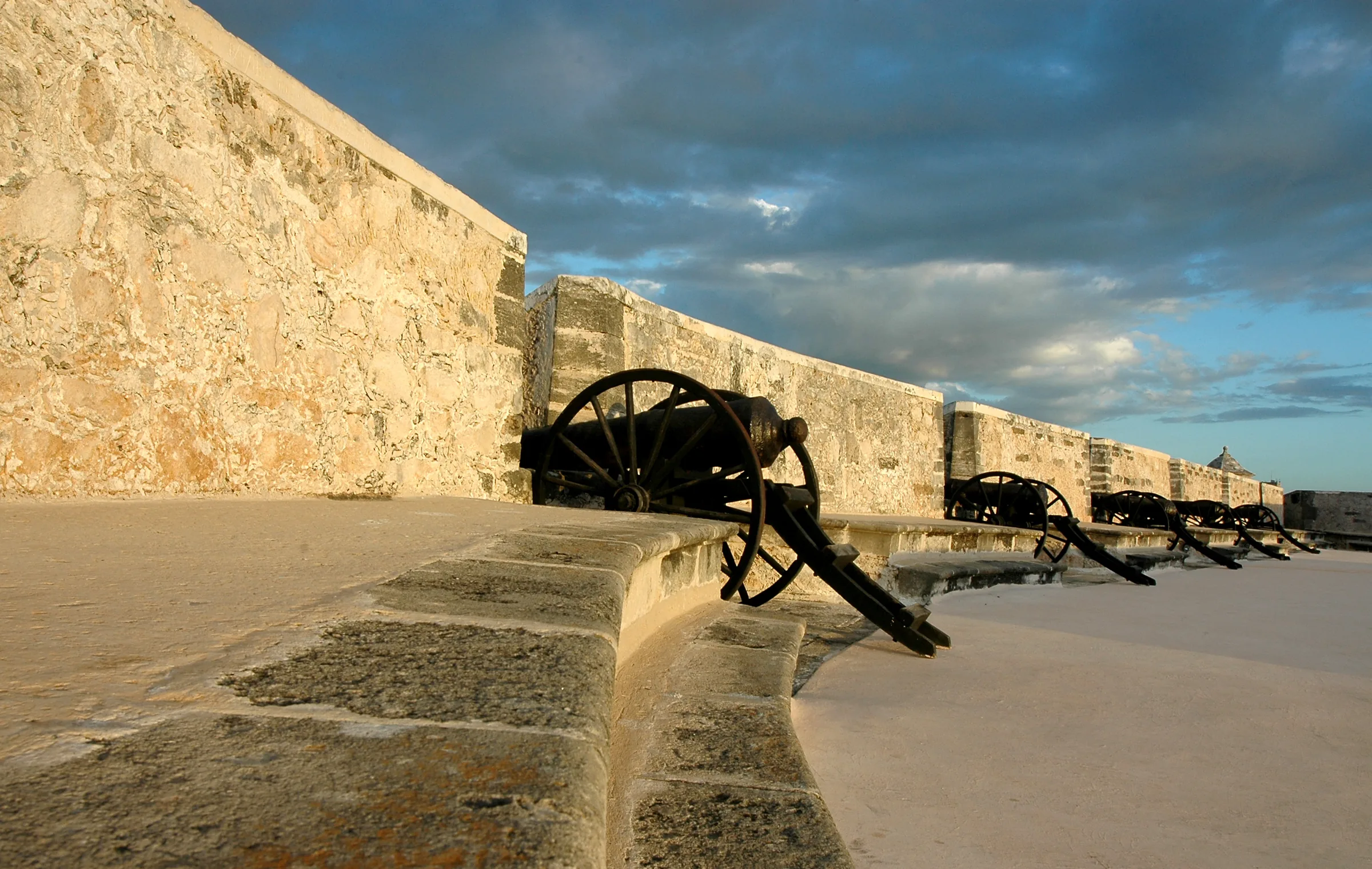 Cannons along the stone parapet of Fort San Miguel, in Campeche, under a cloudy sky