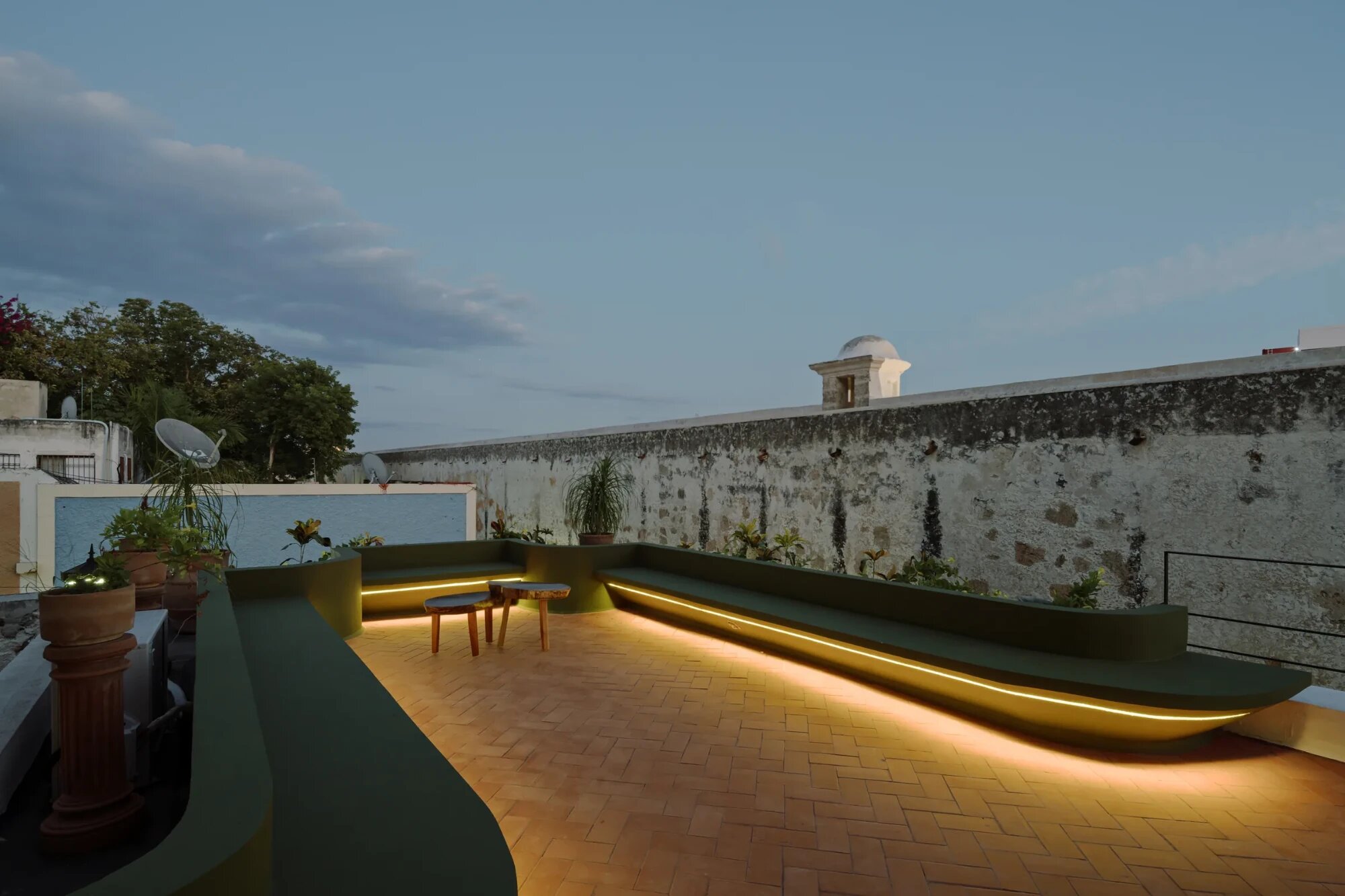 Rooftop terrace of Casa Muralla facing Campeche’s city wall, with lit benches at dusk