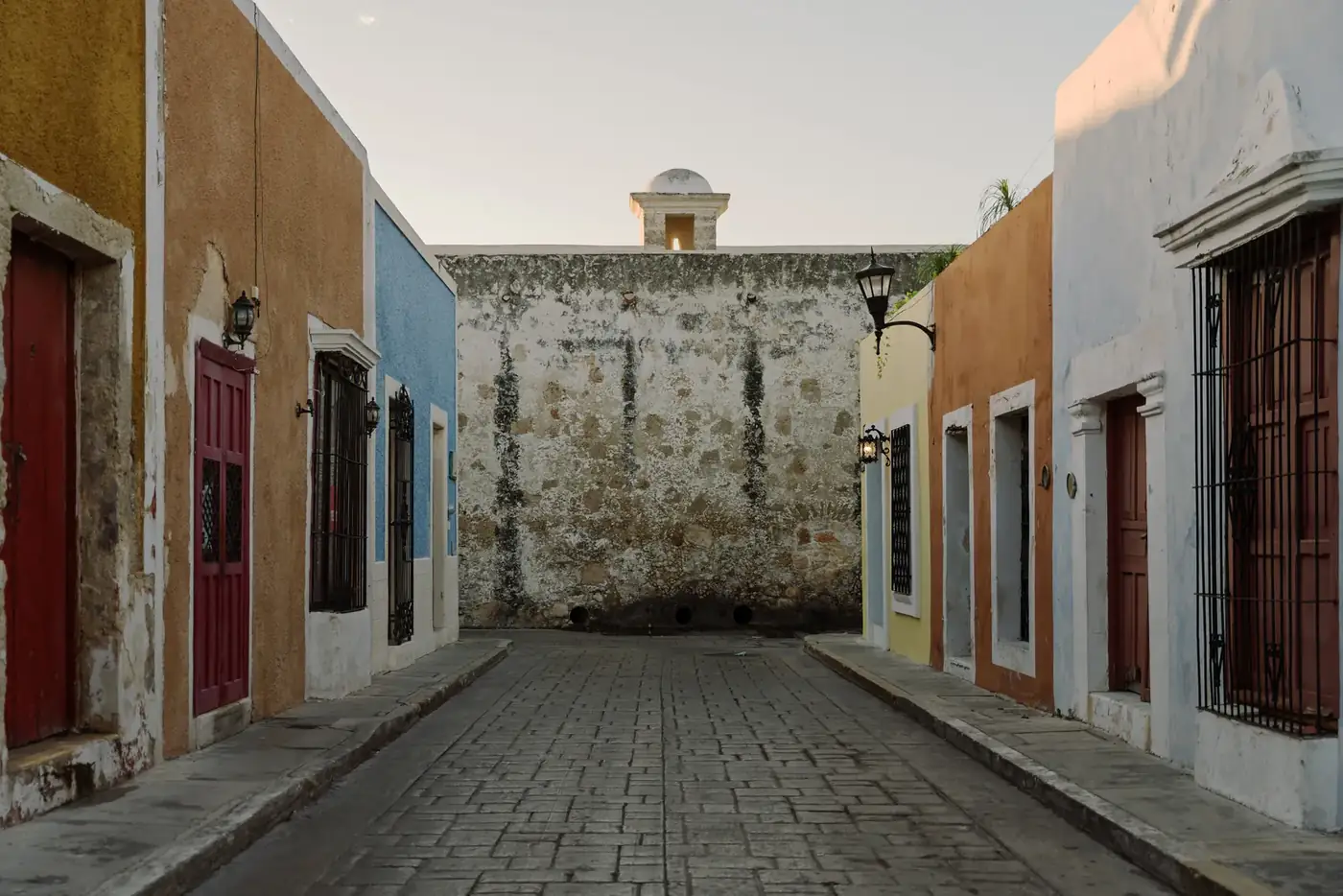 Calle tranquila del centro de Campeche al atardecer, con la muralla al fondo
