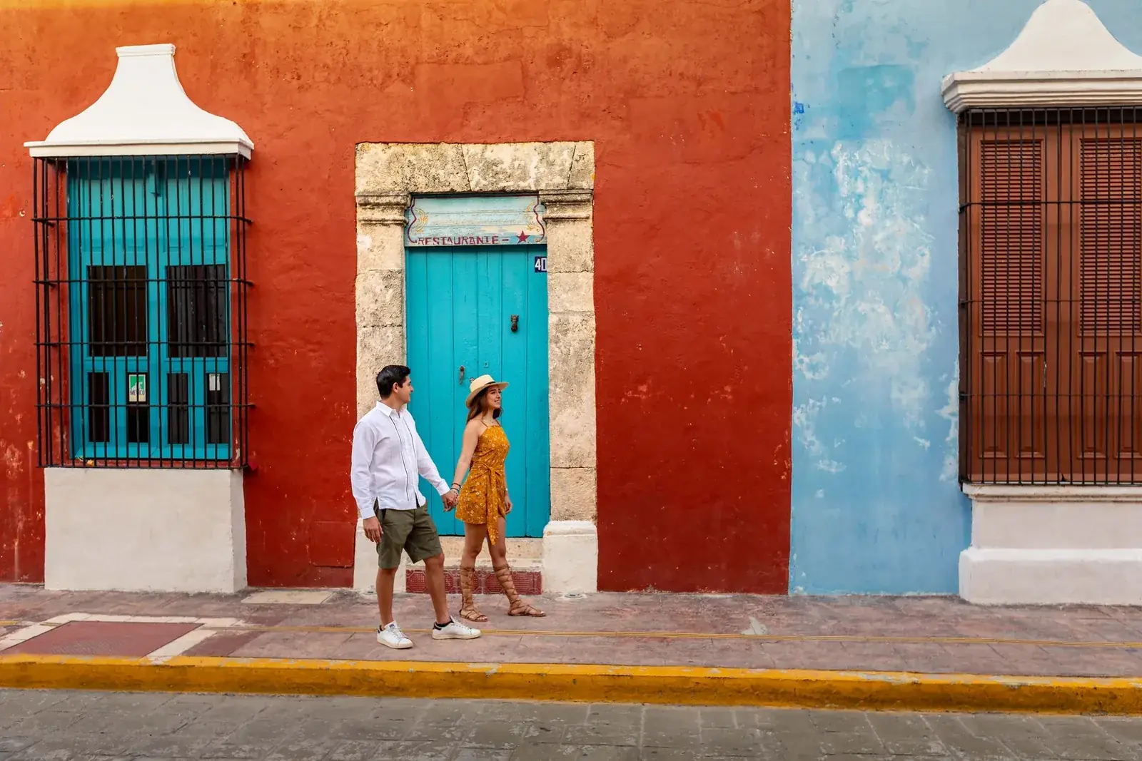 Pareja caminando frente a las fachadas de colores del centro histórico de Campeche